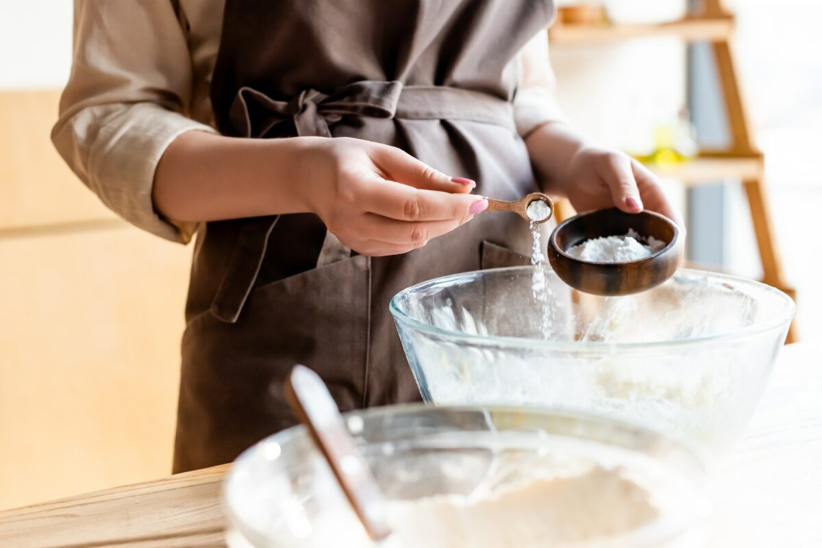 cropped view of woman adding baking powder in bowl