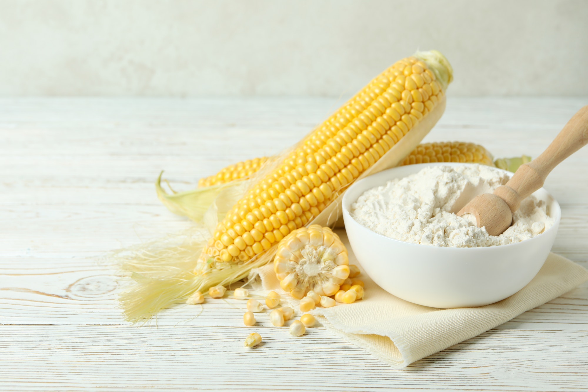 Raw corn and flour on white wooden table