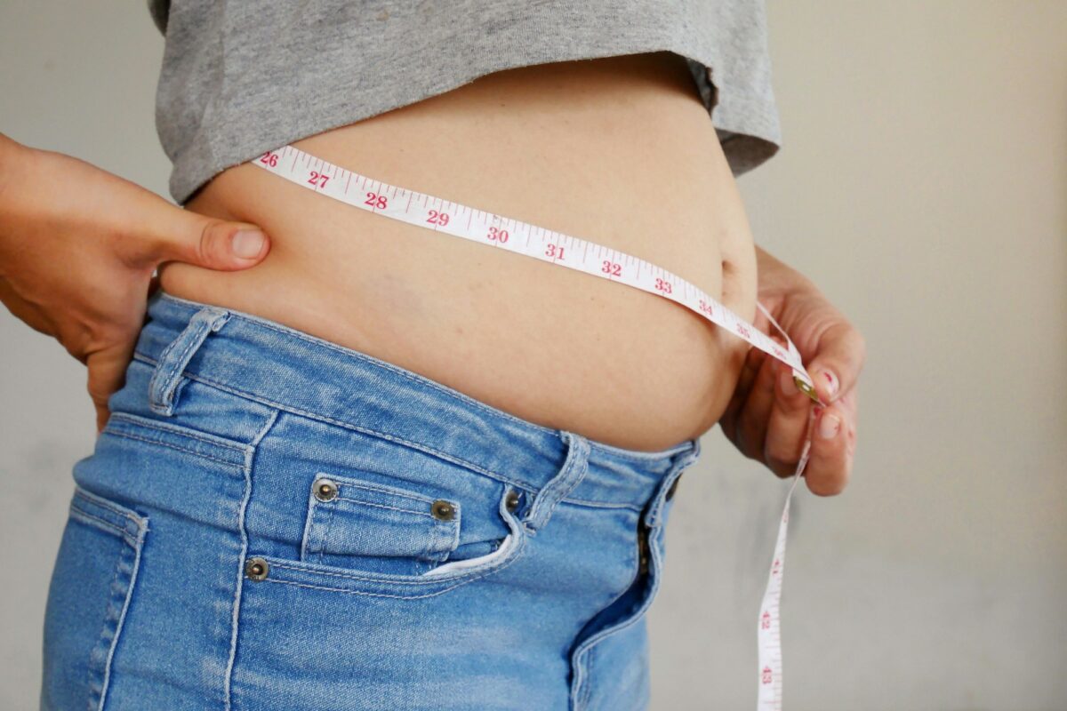 Healthy care. Woman measures her waist with overweight belly and abdomen.