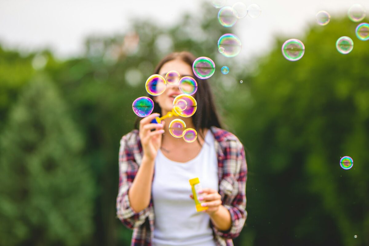 The happy woman blows bubbles on the nature