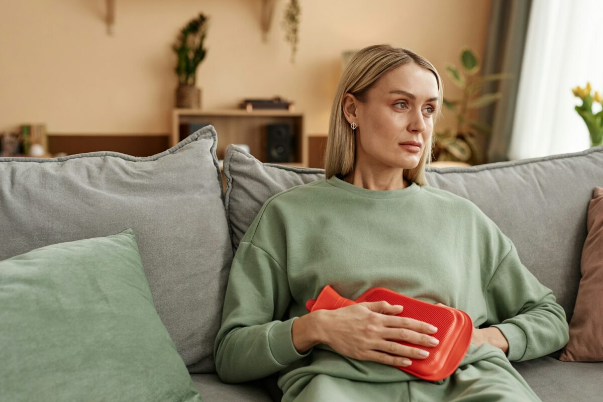Woman Holding Red Hot Water Bottle to Stomach